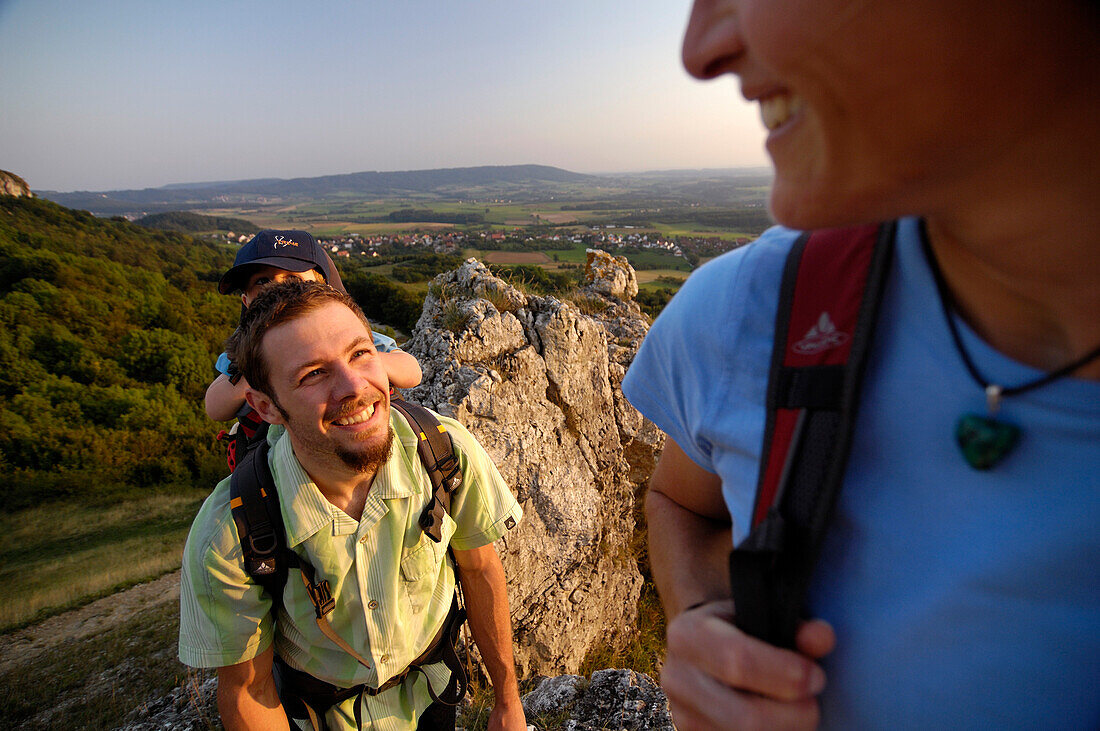 Junge Familie wandert auf einem Berg im Abendlicht, Walberla, Bayern, Deutschland, Europa