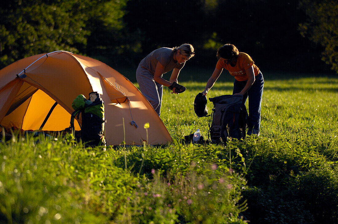 Two woman next to a tent on a meadow, Franconian Switzerland, Bavaria, Germany, Europe