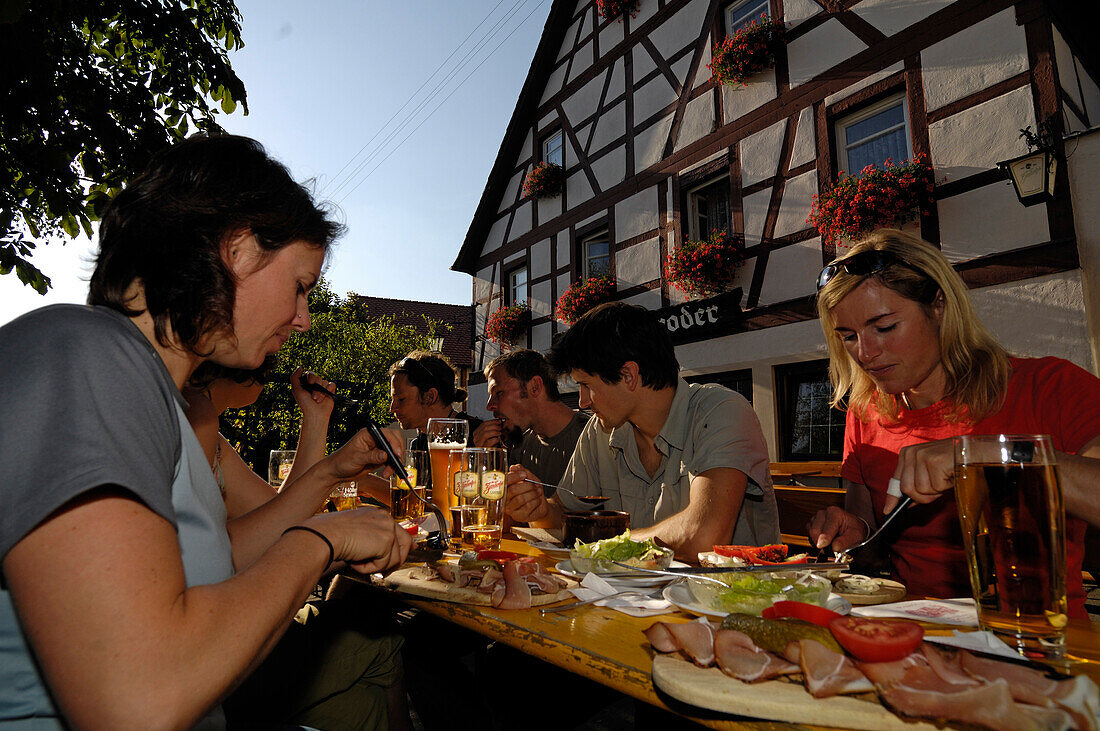 Menschen essen in einem Biergarten vor einem Fachwerkhaus, Fränkische Schweiz, Bayern, Deutschland, Europa