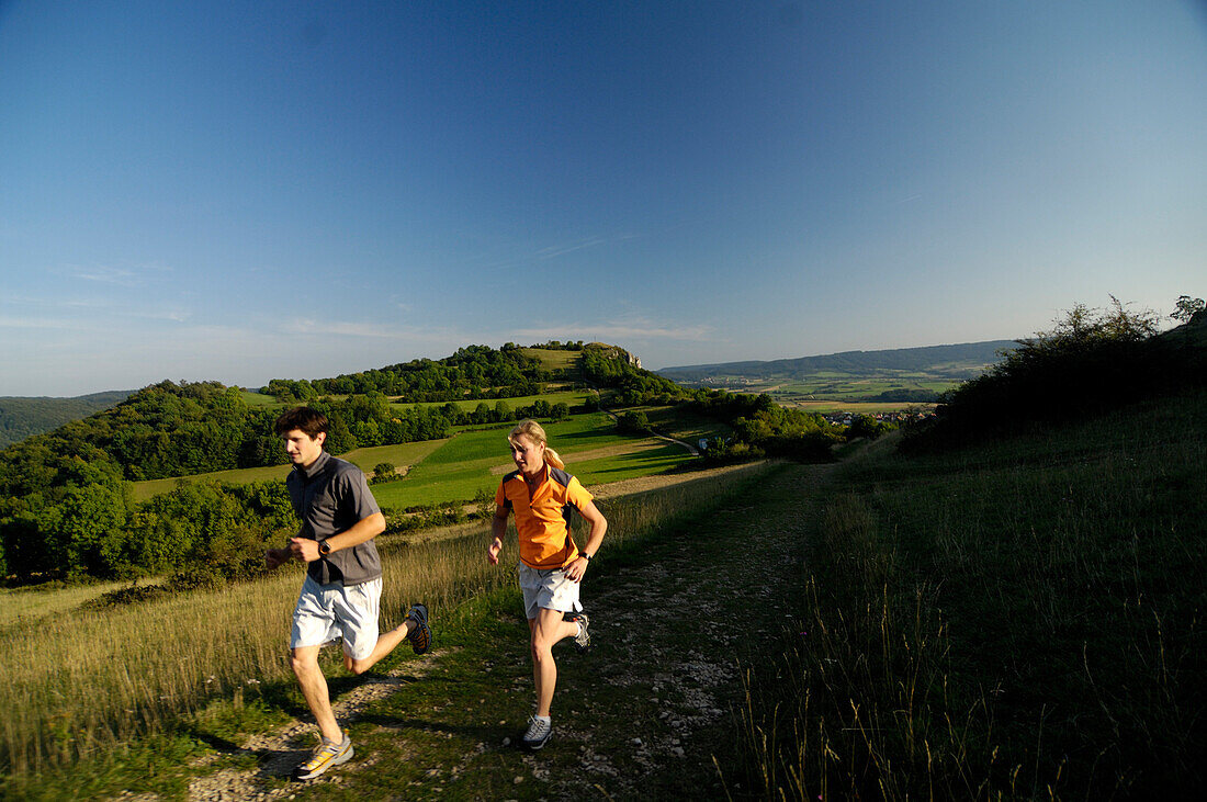 Paar joggt in idyllischer Landschaft, Fränkische Schweiz, Bayern, Deutschland, Europa