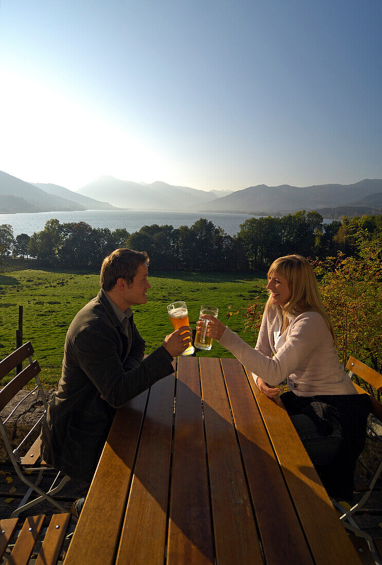 Junges Paar in einem Biergarten im Sonnenlicht, Tegernsee, Bayern, Deutschland, Europa