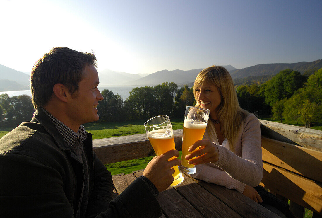 Junges Paar in einem Biergarten im Sonnenlicht, Tegernsee, Bayern, Deutschland, Europa
