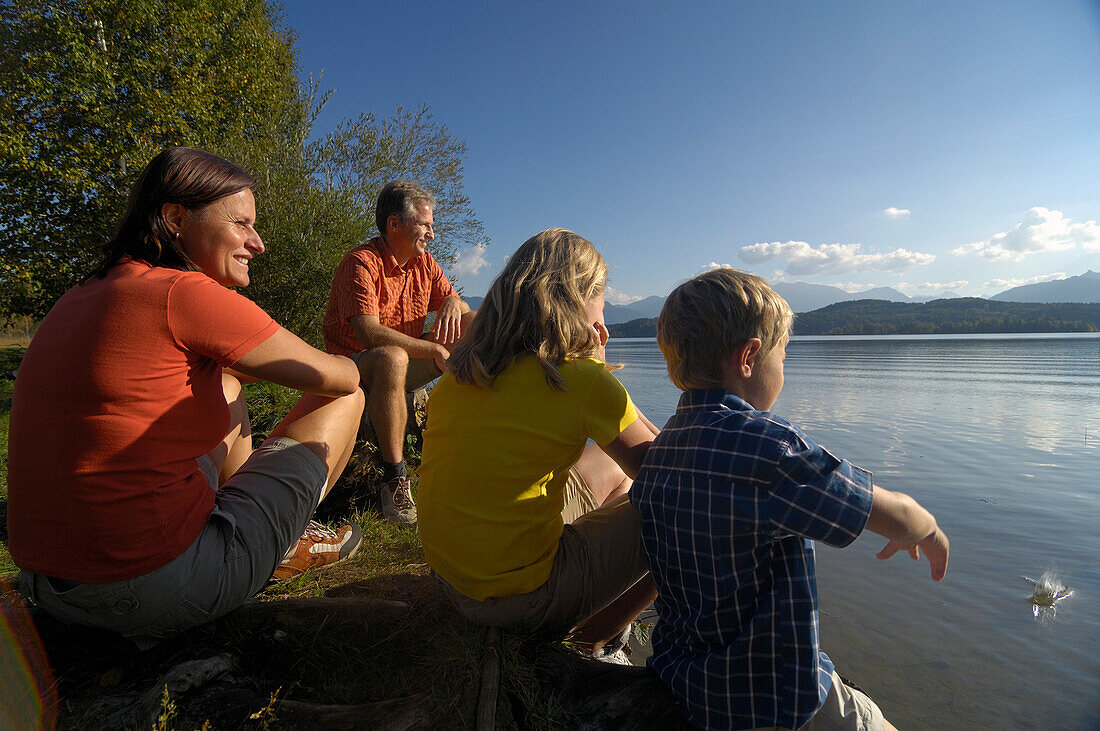 Familie sitzend am Staffelseeufer, Staffelsee, nahe Murnau, Oberbayern, Bayern, Deutschland