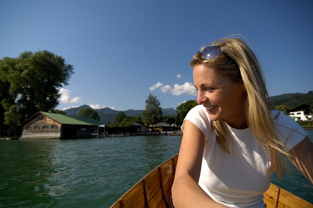 Woman rowing a boat in lake Tegernsee, Boat house in the background, Lake Tegernsee, Upper Bavaria, Bavaria, Germany