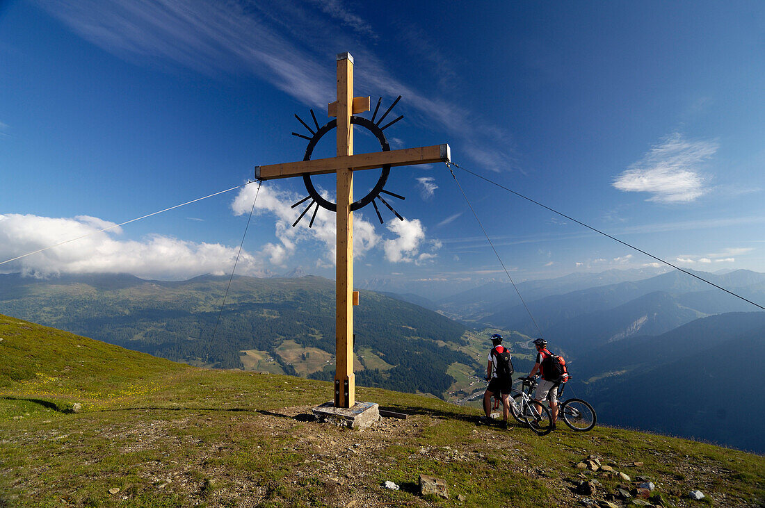Two people on a mountain bike tour at the summit cross, Sattelberg, Brenner, Tyrol, Austria