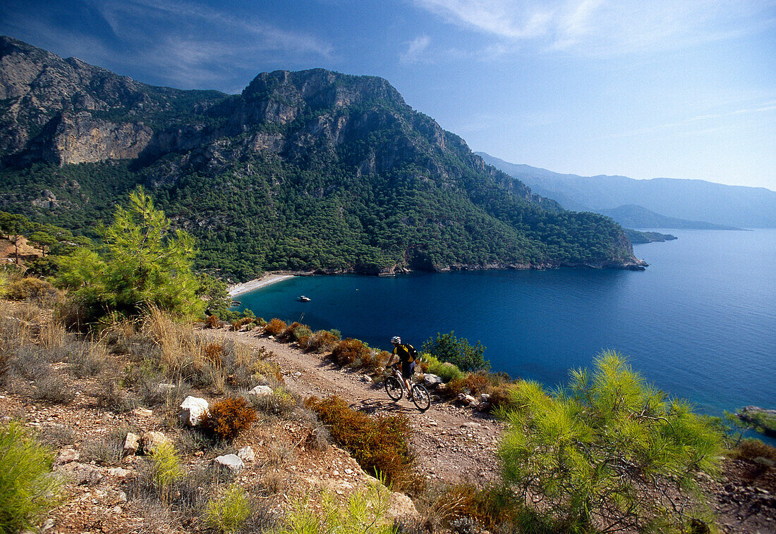Mountain biker in front of Kabak Beach in a bay, Lycian coast, Turkey, Europe