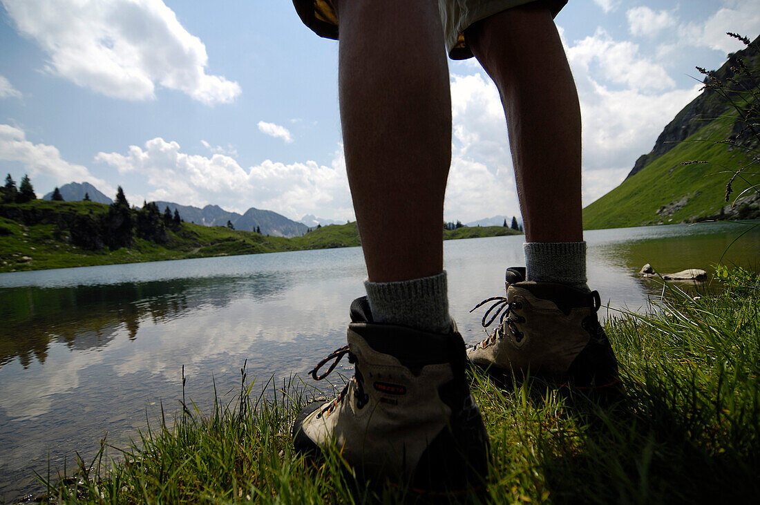 View at the legs of a hiker in front of a mountain lake, Allgaeu Alps, Bavaria, Germany, Europe