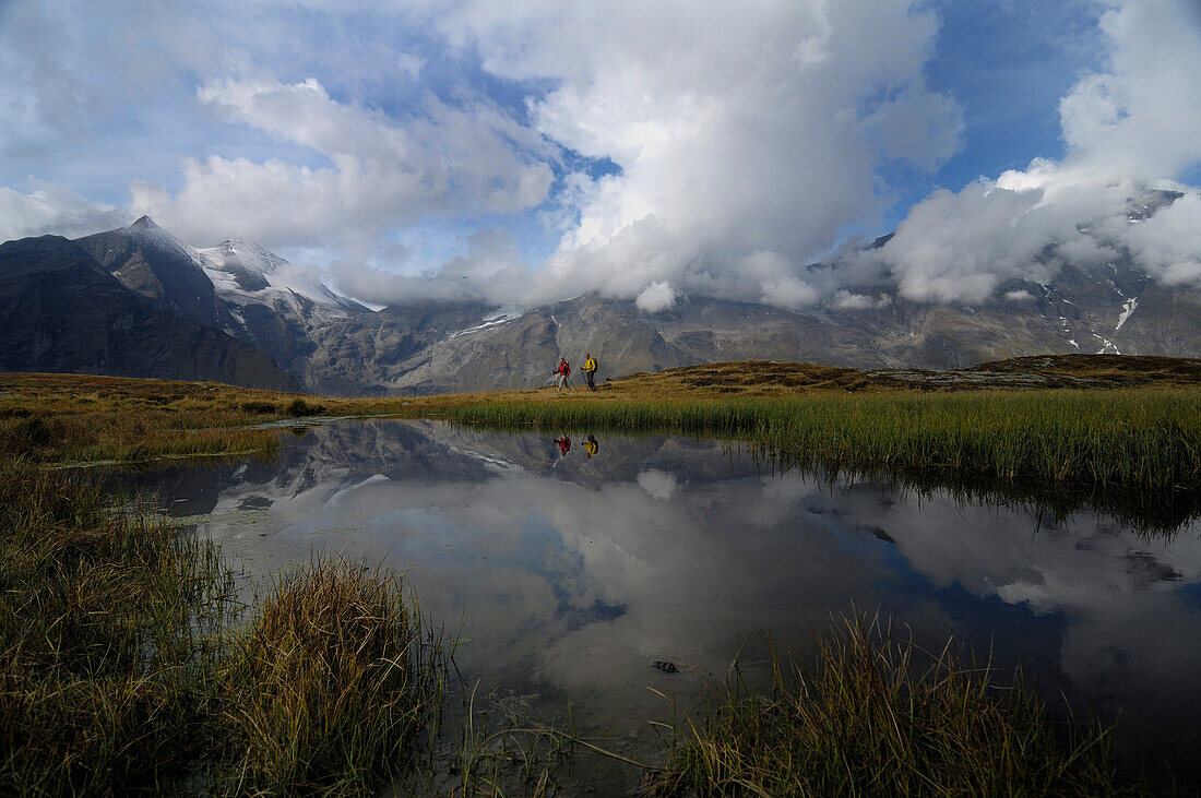 Hikers in front of a mountain lake under clouded sky, Hohe Tauern, Austria, Europe