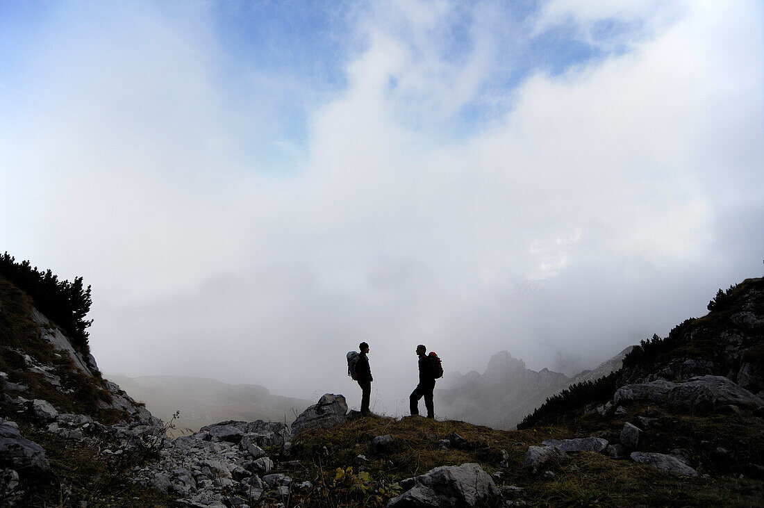 Wanderer mit Rucksack vor wolkenverhangenen Bergen, Wettersteingebirge, Bayern, Deutschland, Europa