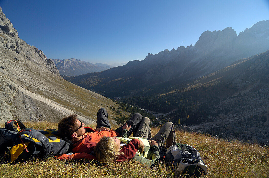 Wanderer liegen auf einer Bergwiese im Sonnenlicht, Val di Fassa, Rosengarten, Dolomiten, Südtirol, Italien, Europa