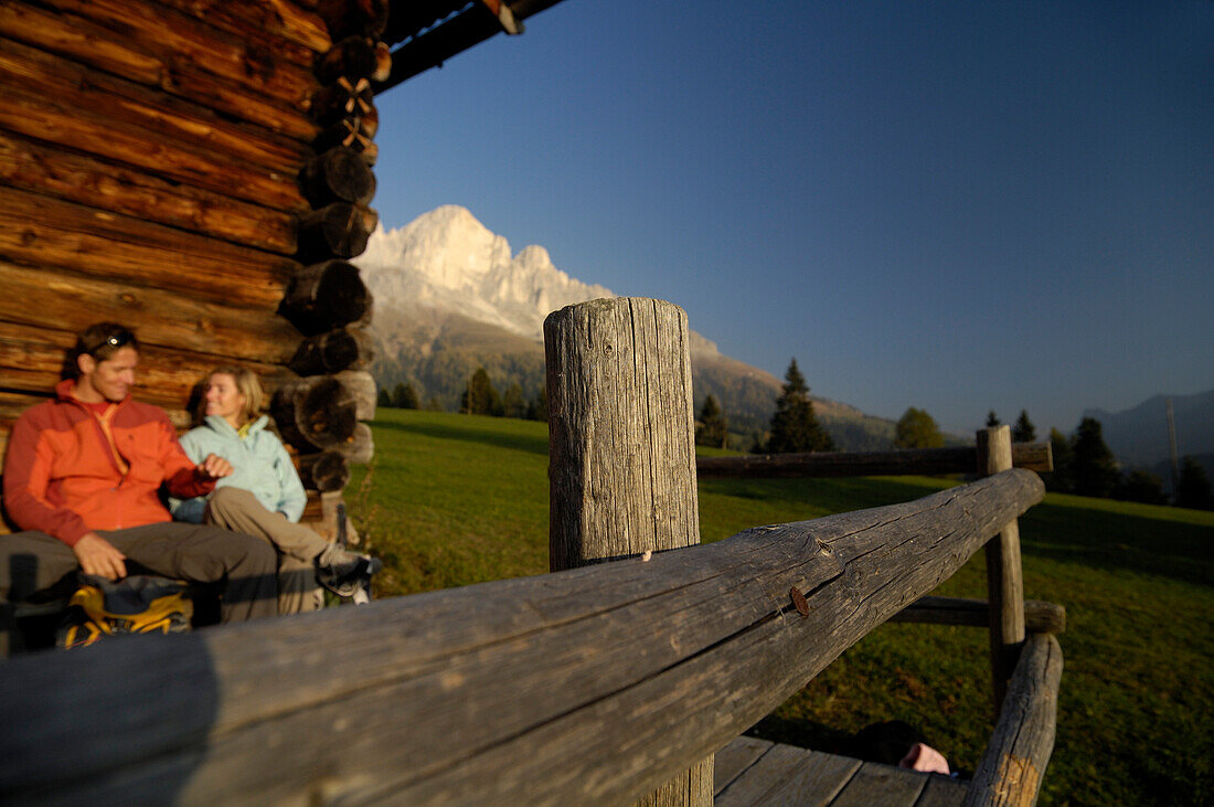 Paar rastet vor einer Hütte, Rosengarten, Dolomiten, Trentino-Südtirol, Italien