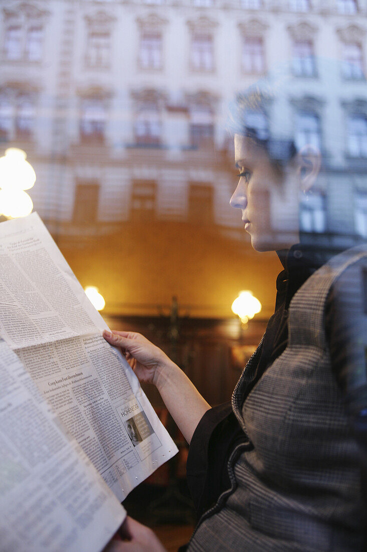 Mid adult woman reading a newspaper in a cafe, Vienna, Austria