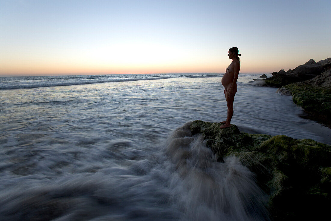 Schwangere Frau steht auf Felsen am Strand, Sonnenuntergang, Strand bei Conejo, Baja California Süd, Mexiko