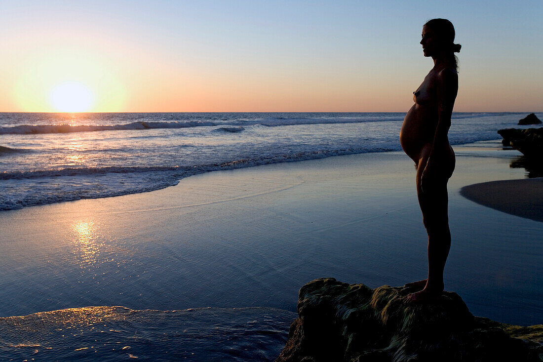 Schwangere Frau steht auf Felsen am Strand, Sonnenuntergang, Strand bei Conejo, Baja California Süd, Mexiko