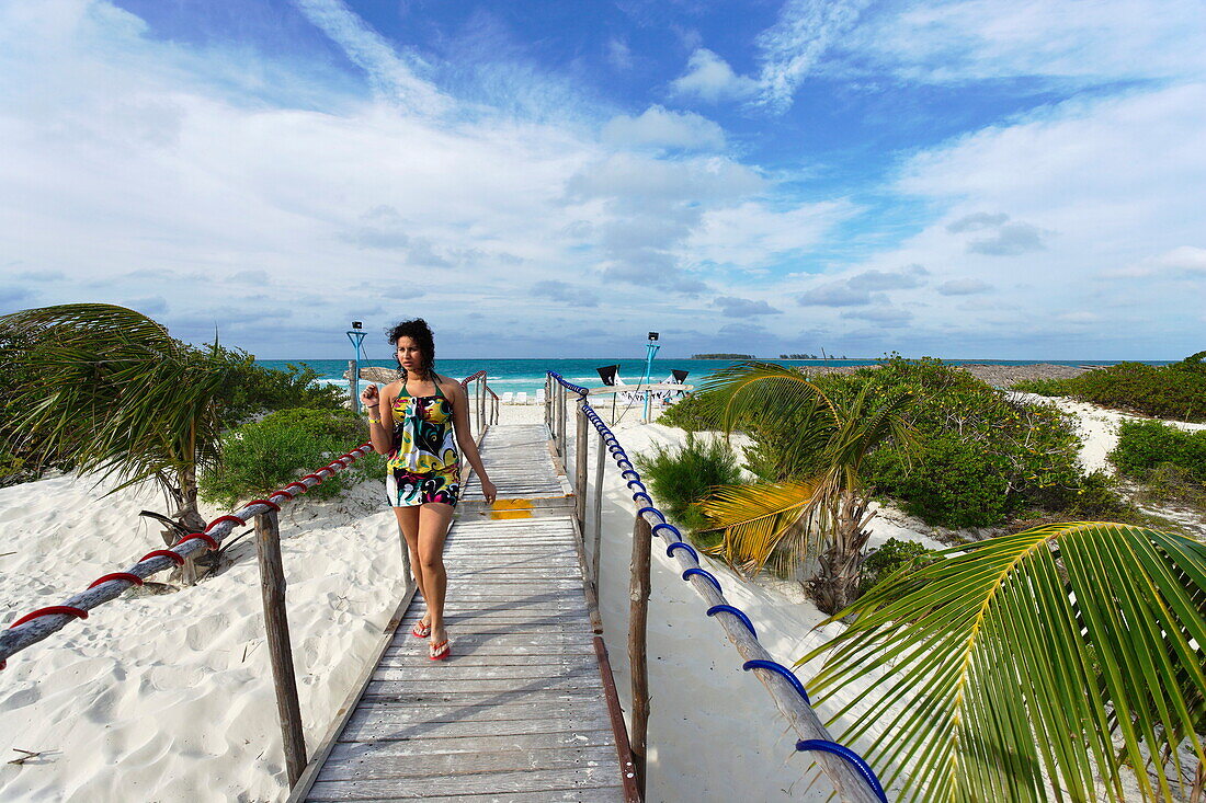 Woman walking over boardwalk along sandy beach, Cayo Guillermo, Ciego de Avila, Cuba, West Indies