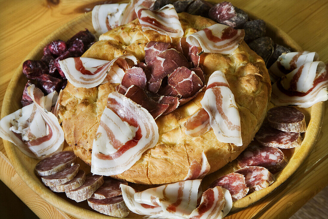 Focaccia (typical salted bread) with cold meats: coppa (similar to ham),  pancetta and mocetta (cured meats). Aosta Valley. Italy