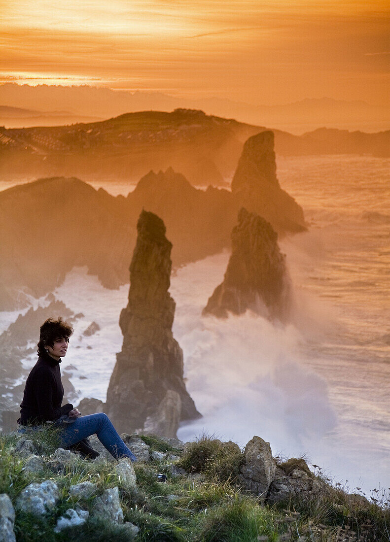 young woman looking from a rocky coast  Liencres, Cantabria, Spain, Europe