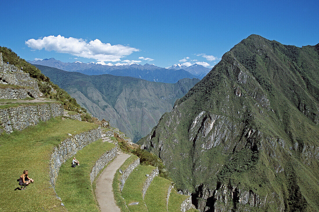 Visitors sitting on terraces at Machu Picchu, Peru