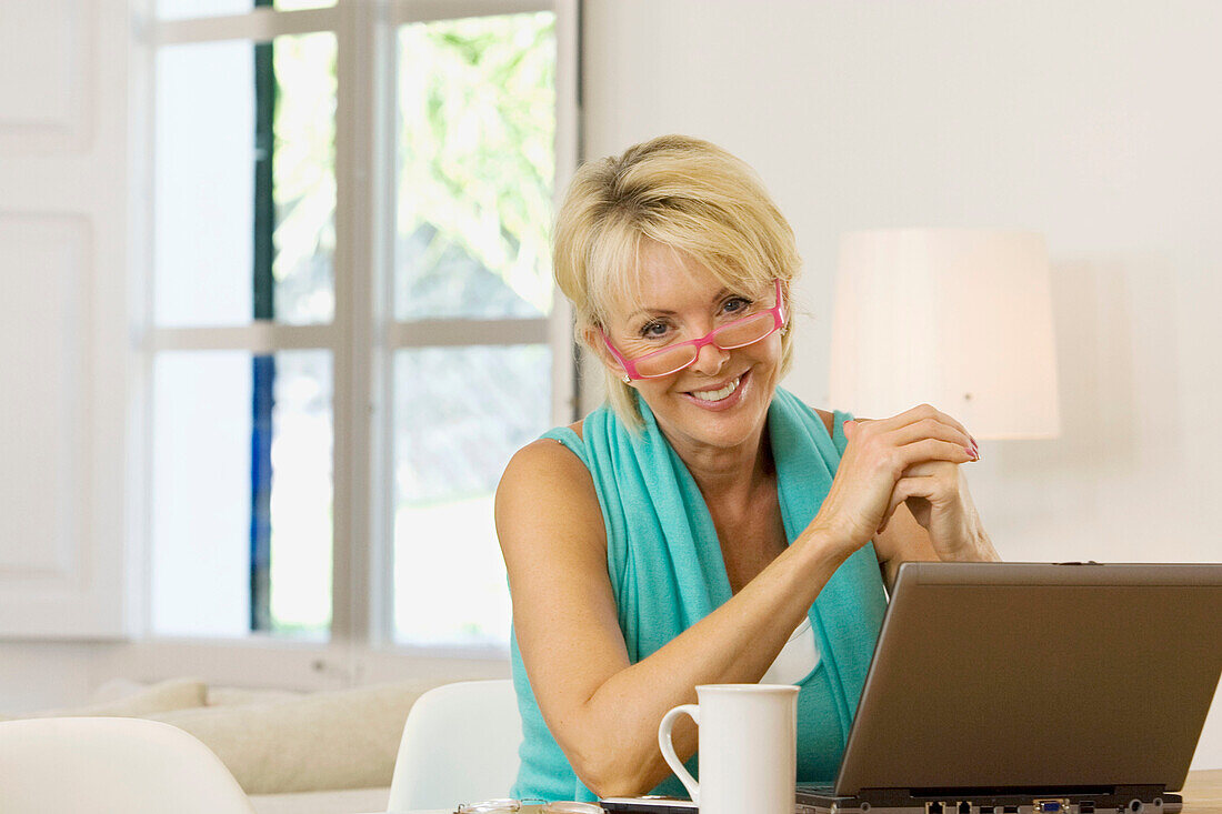 Adult, Adults, At home, Blonde, Blondes, Caucasian, Caucasians, Color, Colour, Computer, Computers, Contemporary, Cup, Cups, Daytime, eyeglasses, Facing camera, Fair-haired, Female, glasses, grin, grinning, Hobbies, Hobby, Home, human, indoor, indoors, in