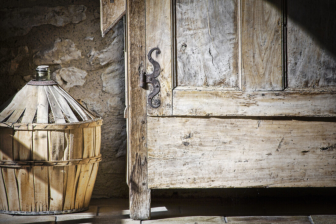 Composition with a carafe of wine and an old cabinet in a corner of an old stone house in the year 1740 in a rural setting.