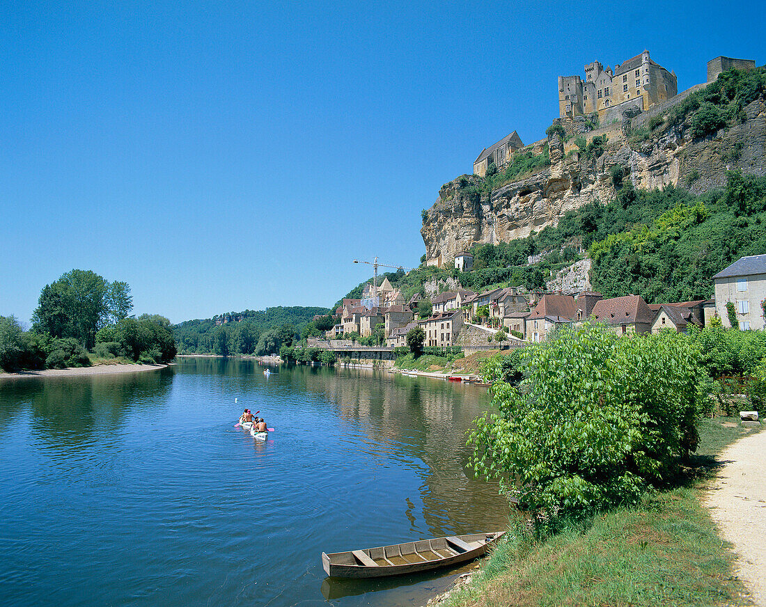 River with canoes and town on hillside, Beynac-et-cazenac, The Dordogne, France