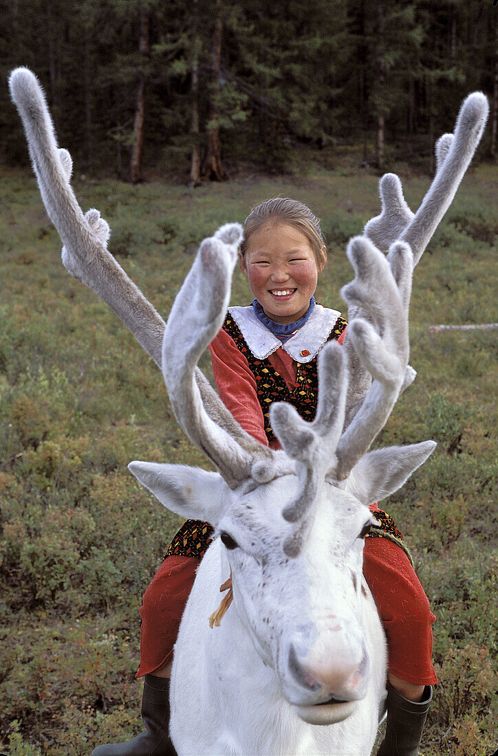 Tsaatan girl riding a reindeer. Red taiga. Khovsgol province. Mongolia