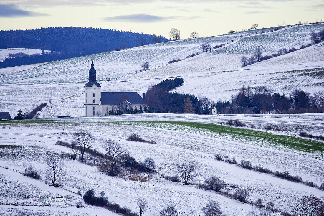 Church between snow-covered fields, Mildenau, Ore Mountains, Saxony, Germany