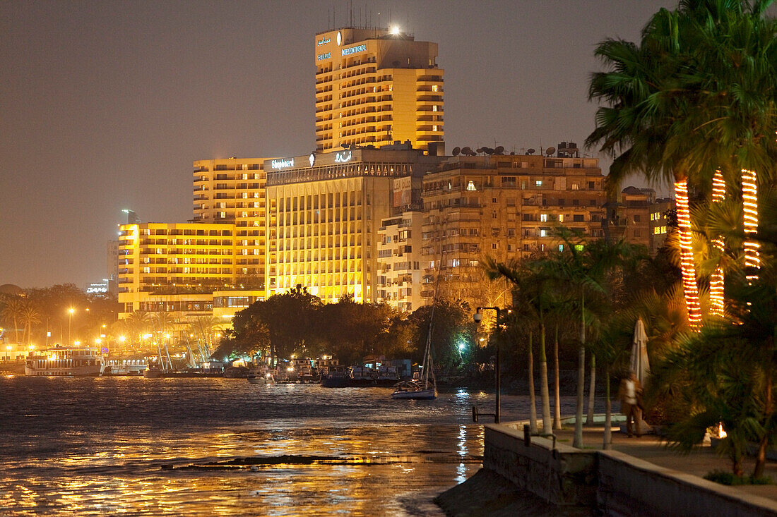 Promenade am Nil unter Palmen und beleuchtete Gebäude, Kairo, Ägypten, Afrika
