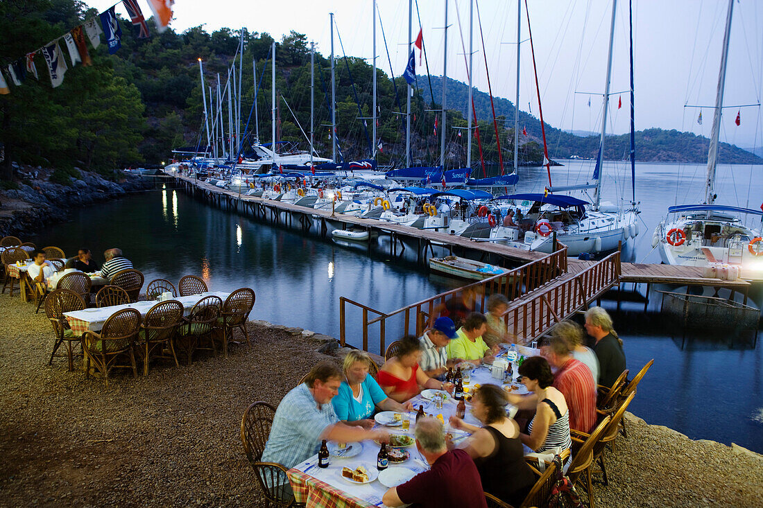 People on the terrace of a restaurant at Sarsala Iskelesi bay, Fethiye, Turkey, Europe