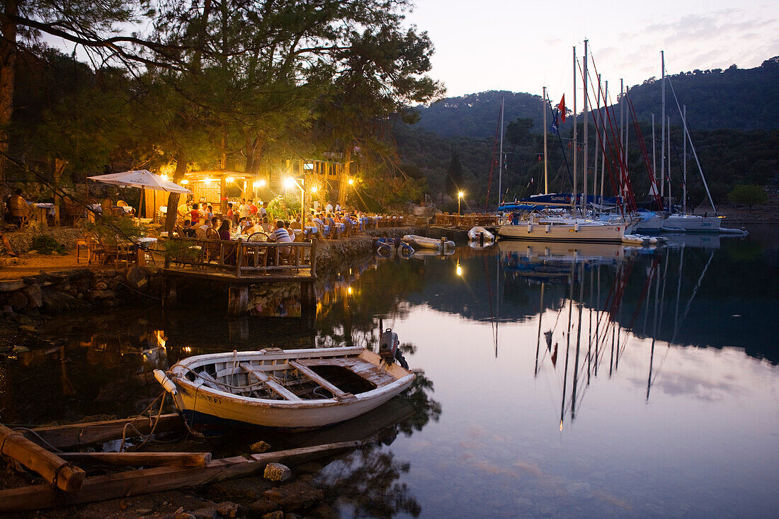 Menschen auf der Terrasse eines Restaurants in einer Bucht mit Anlegestelle, Kapi Creek, Fethiye Bucht, Türkei, Europa