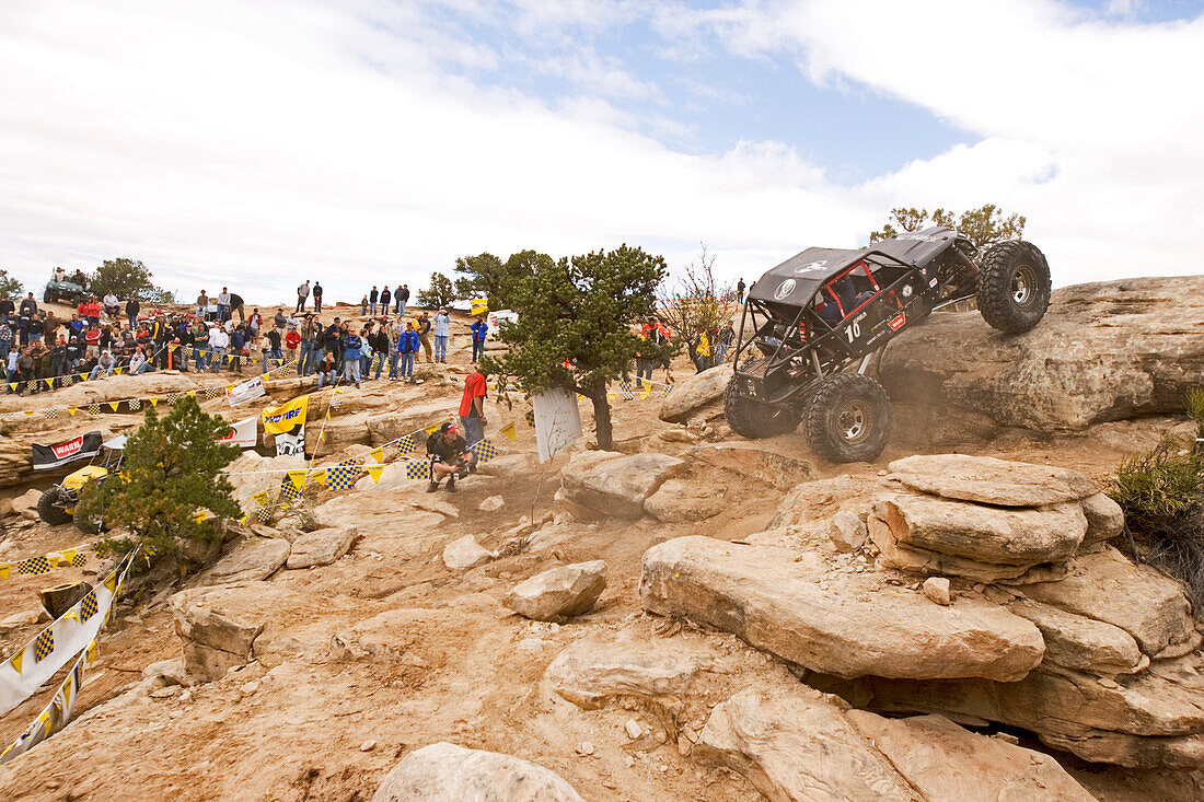 View towards a racing car which is driving over a rock at the Rock Crawling Race, Rock Crawling, Moab, Utah, USA