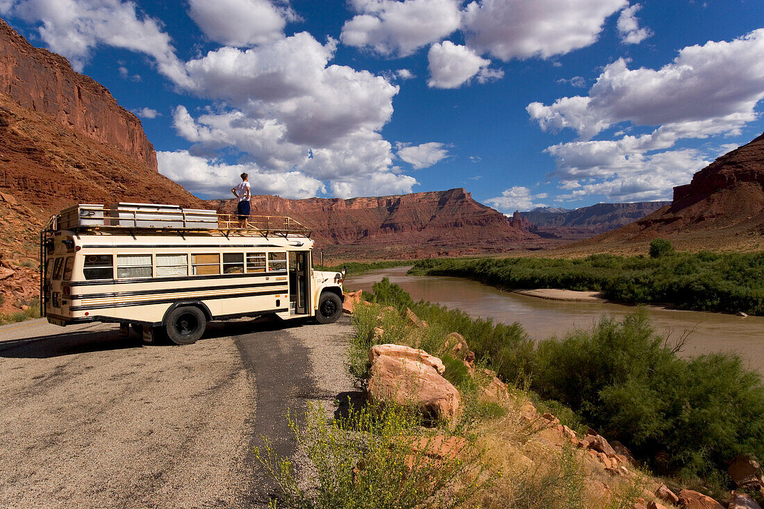 A 18 year old teenager standing on top of an American Schoolbus and looking down the Colorado River towards the Fischer Towers, Utah Scenic Highway 128, Moab, Utah, USA