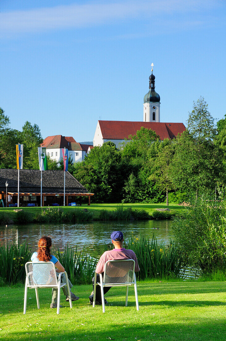Couple sitting near pond in spa gardens, Bad Koetzting, Bavarian Forest, Upper Palatinate, Bavaria, Germany