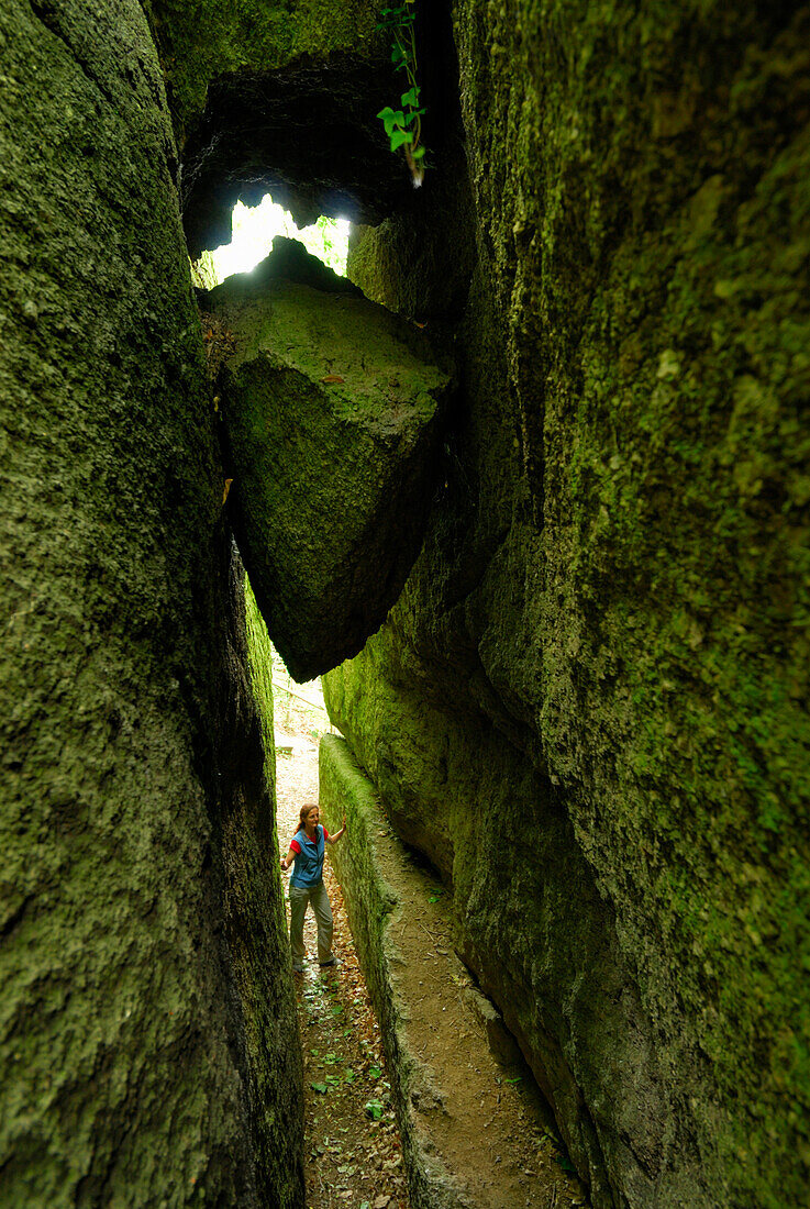 Frau steht in einer Felsspalt unter Klemmblöcken, Felsenpark, Burg Falkenstein, Bayerischer Wald, Oberpfalz, Bayern, Deutschland