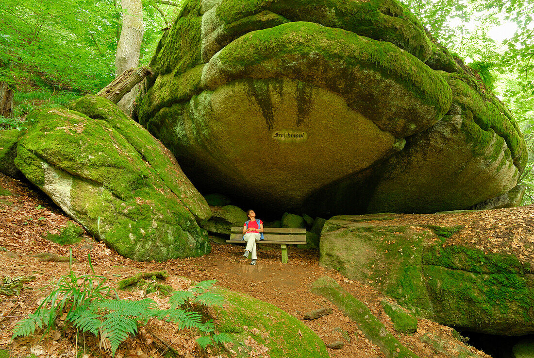 Frau sitzt auf einer Bank unter einem Felsüberhang, Felsenpark, Burg Falkenstein, Bayerischer Wald, Oberpfalz, Bayern, Deutschland