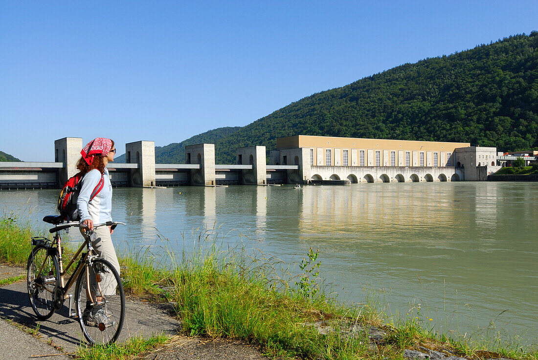 Radfahrerin an der Donau, Kraftwerk Jochenstein im Hintergrund, Donauradweg Passau Wien, Oberösterreich, Österreich
