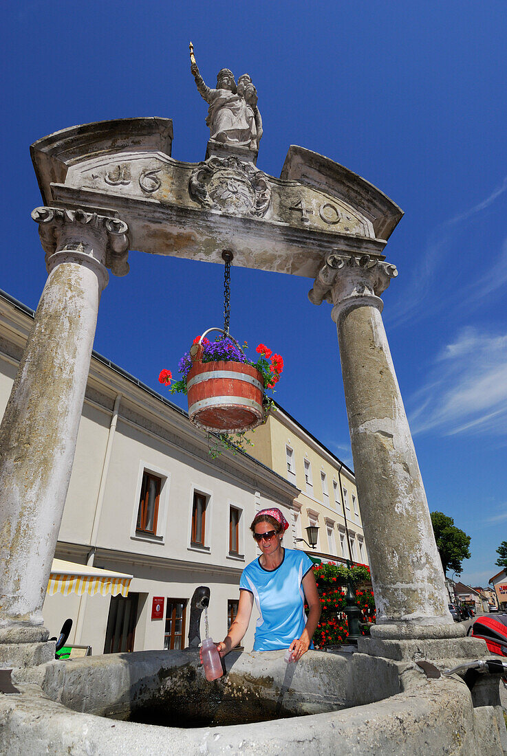 Frau holt Wasser an einem Brunnen, Pöchlarn, Niederösterreich, Österreich