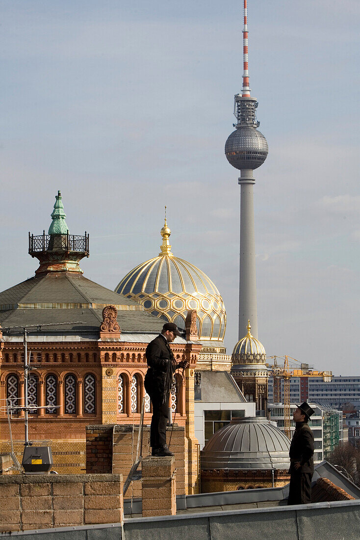 Chimney sweeps standing on roof, dome of New Synagogue, in background, Berlin, Germany