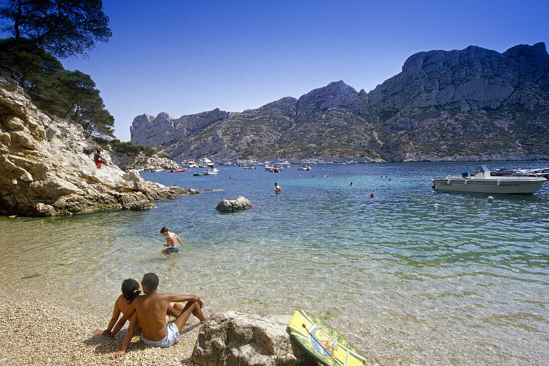 Junges Paar am Strand unter blauem Himmel, Calanque de Sormiou, Côte d'Azur, Provence, Frankreich, Europa