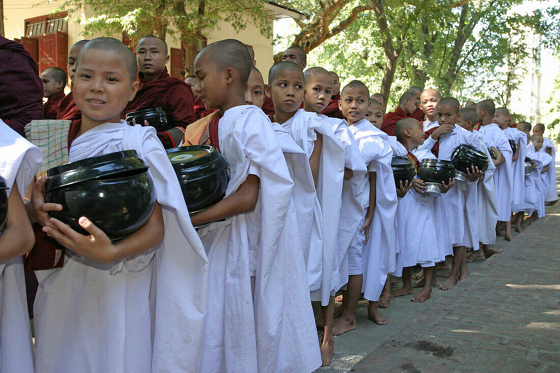 Young Buddhist monks in white robes holding bowls in queue for lunch at 10am, General, people, Burma