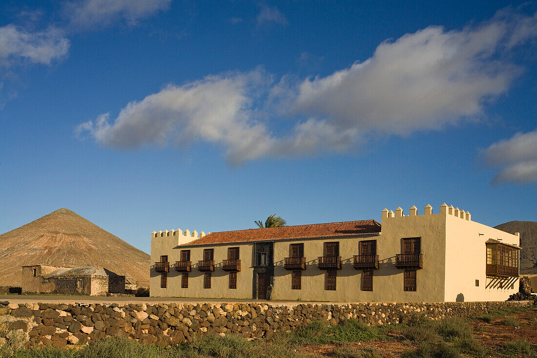 The extinct volcano Montana Oliva behind the historical building Casa de Los Coroneles, La Oliva, Fuerteventura, Canary Islands, Spain, Europe