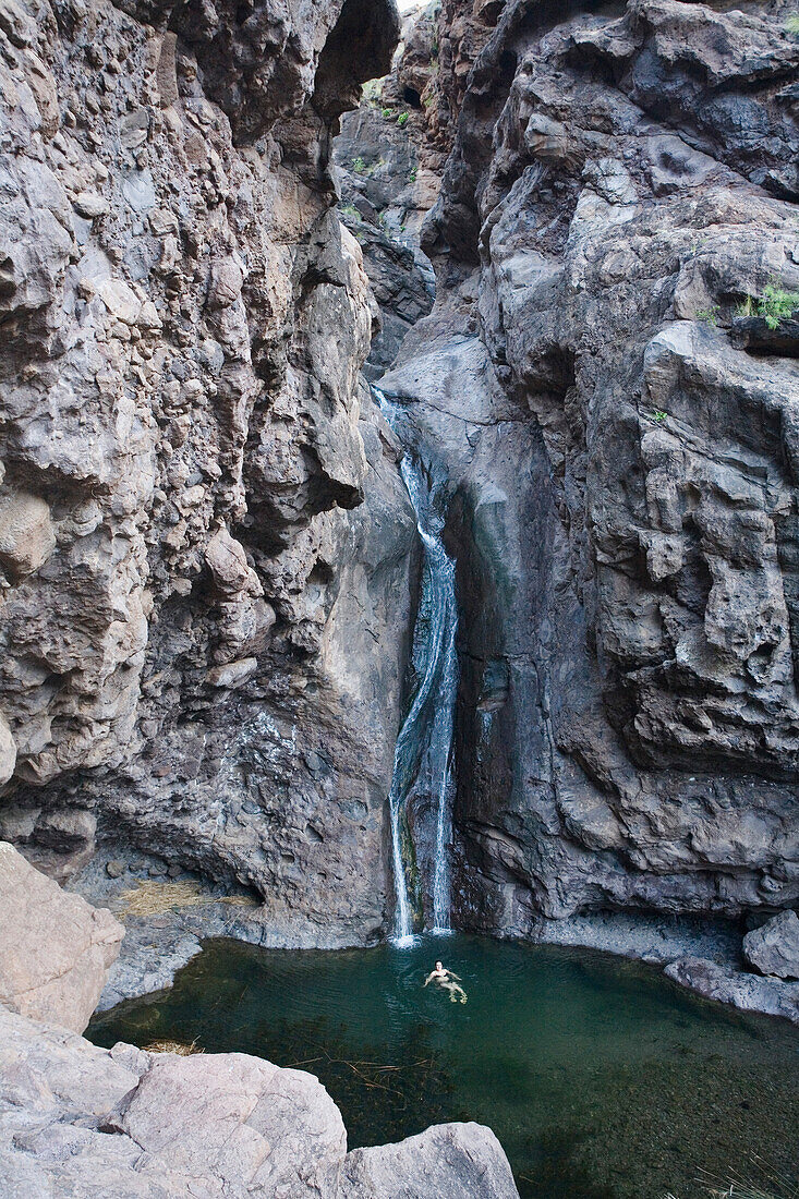Schwimmendes Mädchen in einer Lagune unter einem Wasserfall, Charco Azul, Tal von El Risco de Agaete, Naturpark Tamadaba, Gran Canaria, Kanarische Inseln, Spanien, Europa