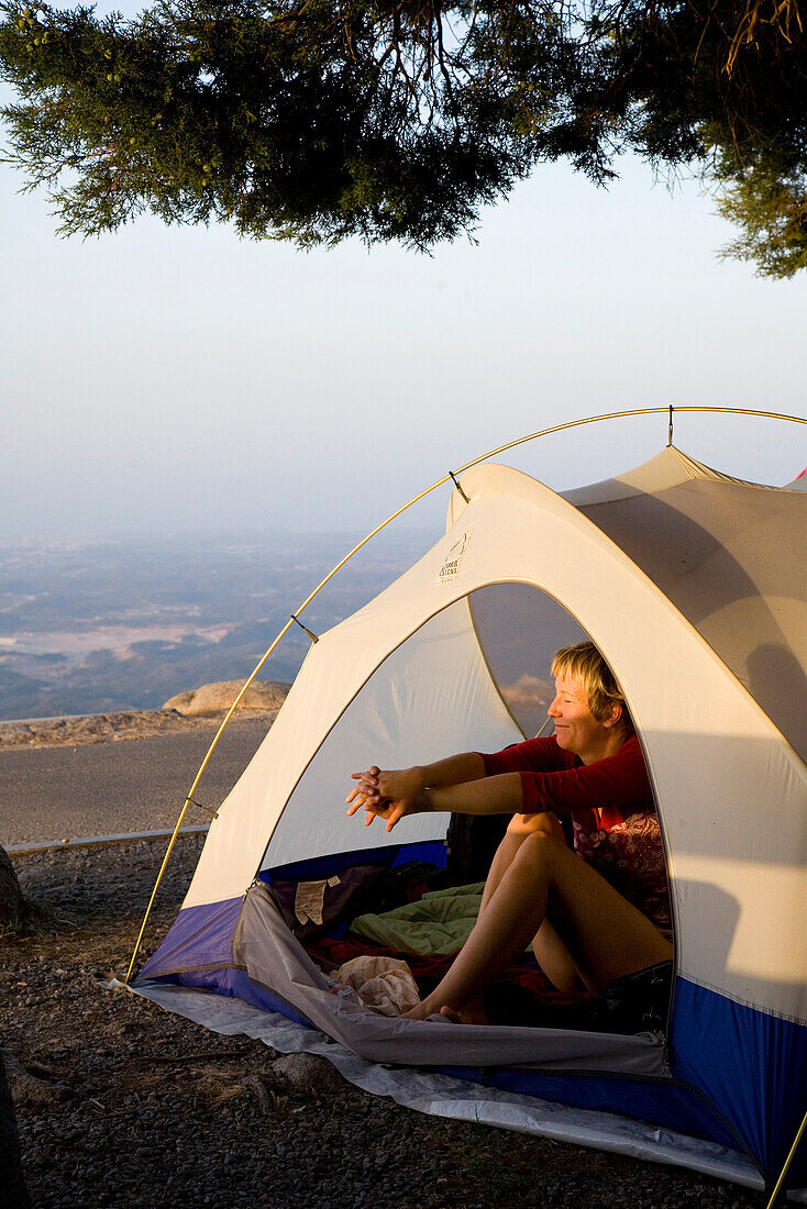 Young women waking up and stretching in her tent, Mount Foia, 902 meters above sea level, Serra de Monchique, MR, Monchique, Algarve, Portugal