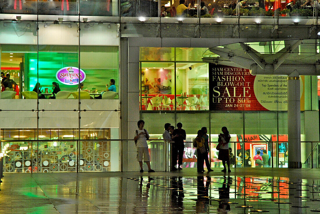 Downtown Bangkok, Siam Center, people on the plattform in front of the Shopping Center with evening lights, Thailand, Asia