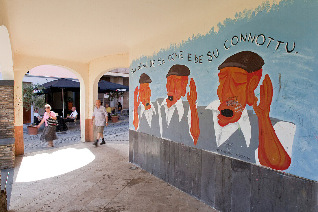 Mural painting and pedestrians in an arcade, Galtelli, Sardinia, Italy, Europe