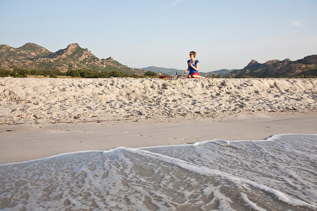 Frau mittleren Alters frühstückt am Strand, Berchidda, Siniscola, Sardinien, Italien, Europa