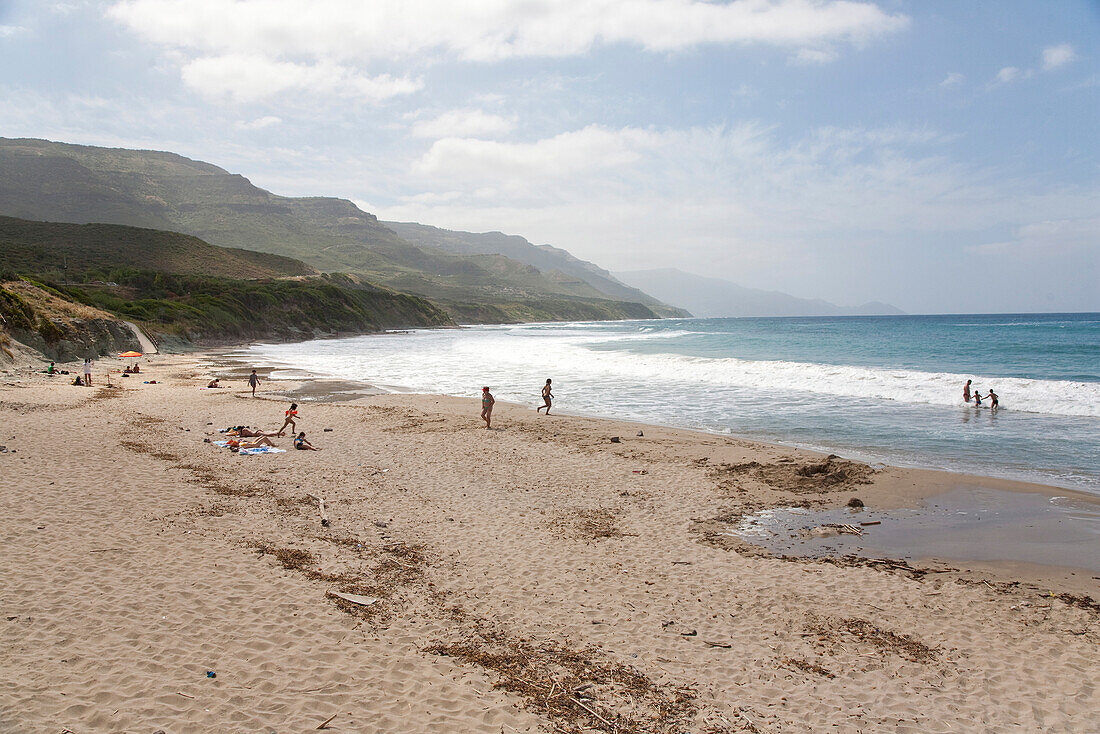 People on a sandy beach under clouded sky, Bosa, Sardinia, Italy, Europe