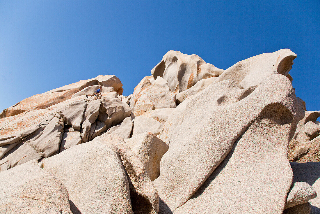 Climber at granitic rocks under blue sky, Capo Testa, Sardinia, Italy, Europe