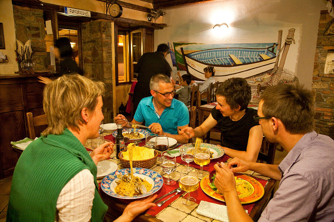 People sitting laughing at a table at a fish restaurant, Posada, Sardinia, Italy, Europe