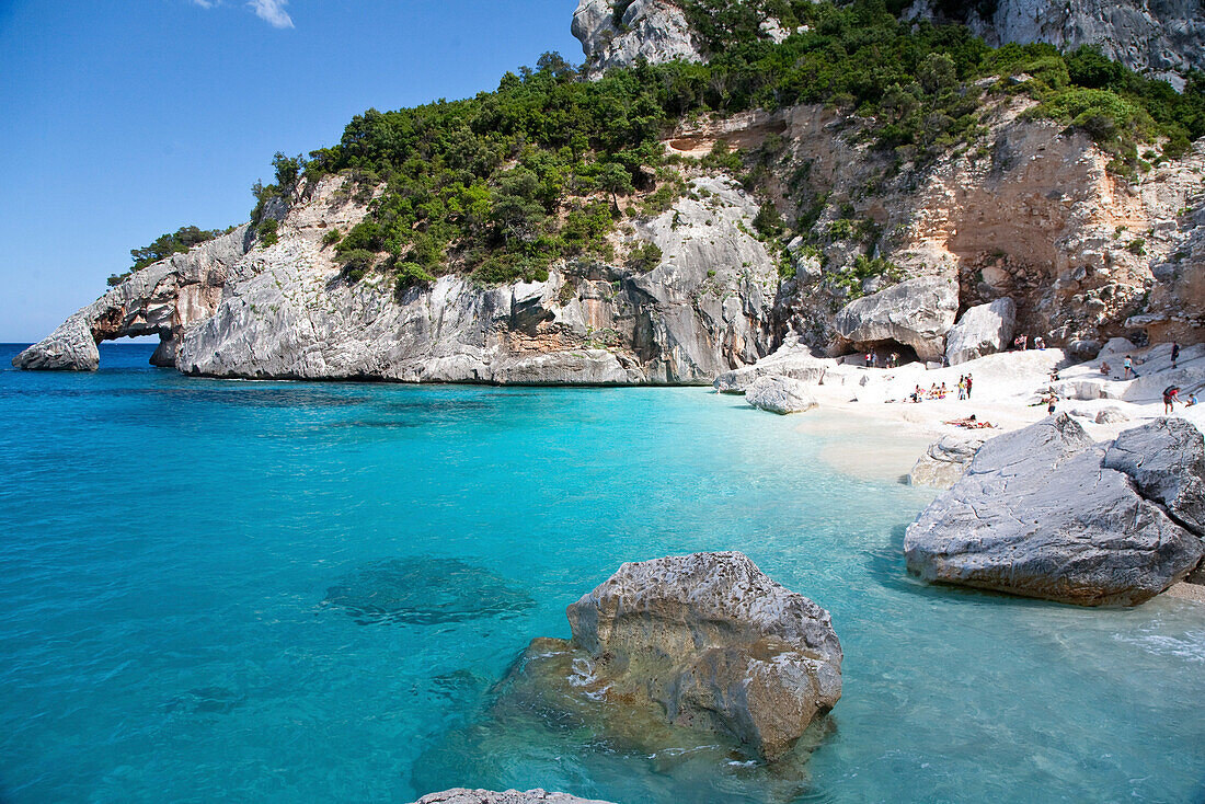 Menschen an einem Sandstrand in einer sonnigen Bucht, Punta Goloritzé, Golfo di Orosei, Sardinien, Italien, Europa